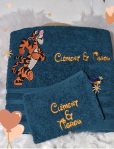 Serviette bleu foncé avec Tigrou et texte brodé en jaune, accompagnée d’un gant assorti.